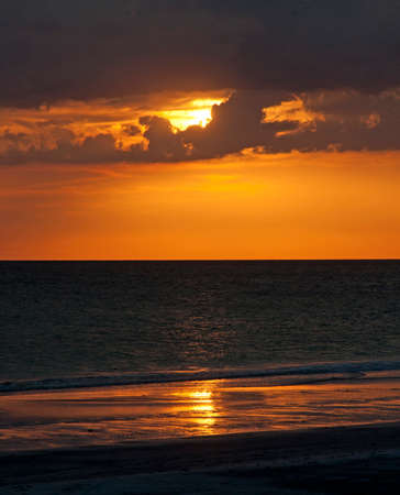 The sun behind dark clouds moments before sunset at the beautiful Clearwater Beachの写真素材
