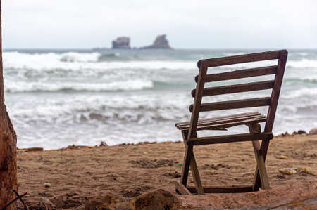 Old wooden beach chair facing the ocean, on an overcast and gloomy morning, Ayampe, Manabi, Ecuadorの写真素材