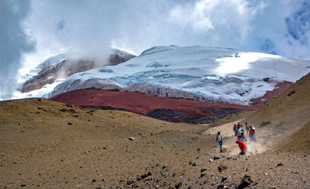 People running down the slopes of the Cotopaxi volcano, on a sunny and cloudy afternoon. Cotopaxi National Park, Ecuador.のeditorial素材