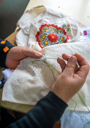 Ibarra, Imbabura Province, Ecuador - November 2013: A craftswoman in her shop, working on designs and sewing to then later add them to clothing and other kinds of crafts.のeditorial素材