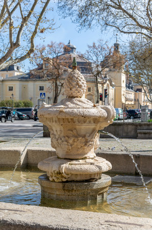 Ornate baroque fountain in the foreground of a village square with the 16th-century Royal Palace of El Pardo, a former hunting lodge, visible in the backgroundの写真素材