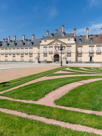 The Renaissance-style main facade of El Pardo Palace overlooking the formal gardens, featuring its ochre walls, steep slate roofs, and meticulously manicured parterresの写真素材