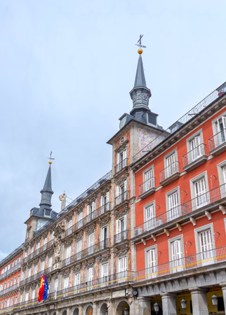 The highly decorated facade of Madrid's Casa de la PanaderÃ­a on the Plaza Mayor, featuring vibrant frescoes, two ornate towers, multiple balconies, and flags flyingの写真素材
