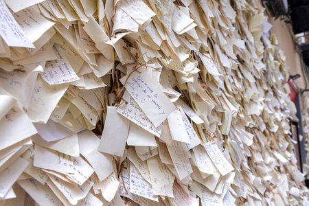 A wall in central Madrid is completely obscured by thousands of small, hand-written paper notes tied up with twine, displaying collective feelings, wishes, and thoughtsの写真素材
