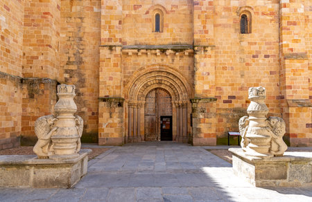 A close-up of the Romanesque side door of Ãvilaâs Church of San Pedro, with a rounded carved archway framed by two low stone pedestals, each topped with a sculpted lion figureの写真素材