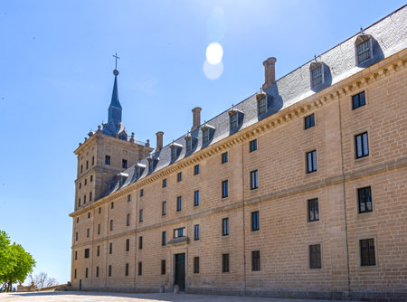 A sunny view of the long granite facade of El Escorial monastery from its main entrance patio in San...