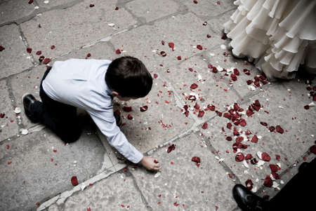 Kid collecting rose petals from the floor in a wedding