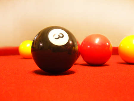 The game of pool number eight black ball with red and yellow blurred in the backgroundの写真素材