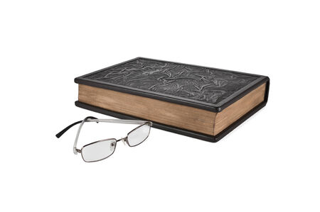 Glasses lie next to the book leather-bound  Isolated on white background の写真素材