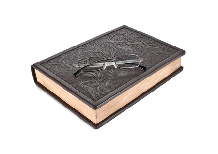 Glasses lie on the closed book leather-bound  Isolated on white background の写真素材