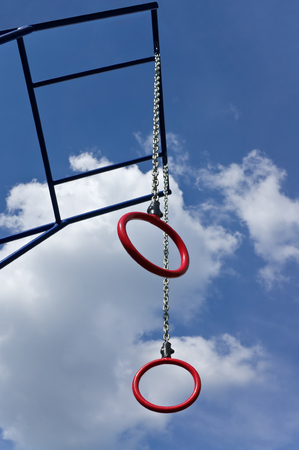 Athletic rings hanging on chains on background of cloudy skyの写真素材