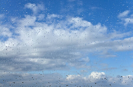 Raindrops on windowpane are on background of cloudy skyの写真素材
