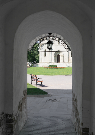 Temple of Christian monastery, bench and lamp through archwayの写真素材