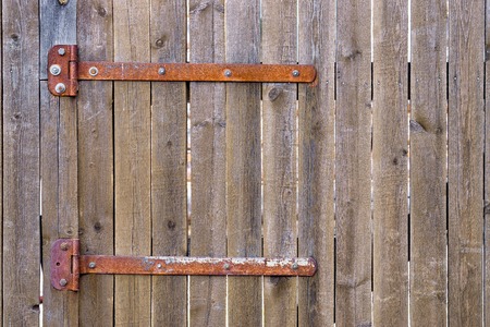 Fragment of closed wooden gate with rusty hingesの写真素材