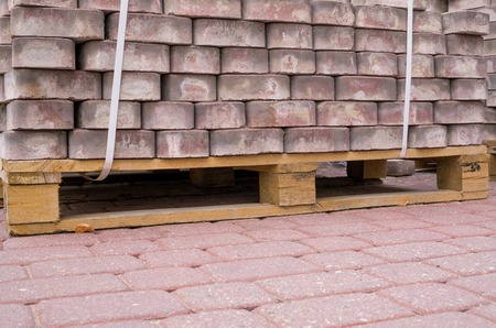 Stack of pink paving tiles on pallet standing on pavementの写真素材