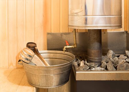 Stove with stones, basin and ladles in steam roomの写真素材