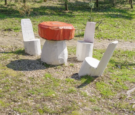 Wooden sculpture of table in shape of mushroom and chairs at forest lawnの写真素材
