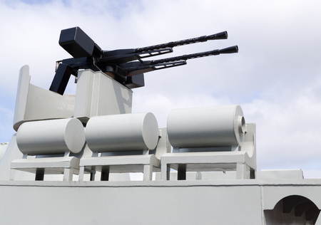 Double-Barrel machine gun is on military torpedo boat against background cloudy sky