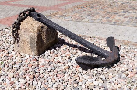 Old anchor lies on stones. Sunny dayの写真素材