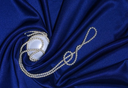 Twisted pearl necklace is on draped blue fabricの写真素材