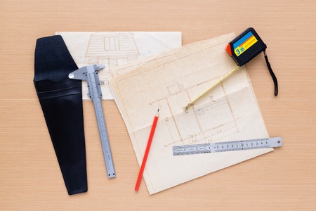 Caliper, measuring tape, ruler, pencil, project house are on wooden surface. View from aboveの写真素材