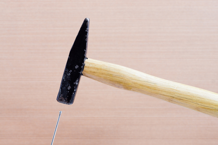 Hammer hitting by nail on background of wooden surface. Blurred backgroundの写真素材