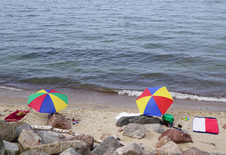 Two multicolored sunshades are on sandy beach on sea shoreの写真素材