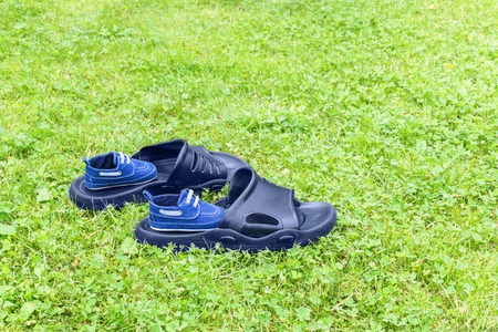 Men's rubber slippers and infant shoes are on lawnの写真素材