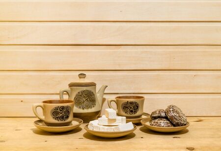 Gingerbreads, marshmallow, ceramic teapot and cup with tea are on wooden background. Copy spaceの写真素材