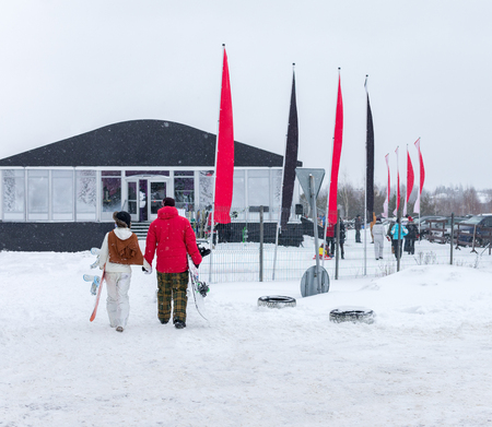 MOSCOW, RUSSIA - JANUARY 25, 2015: Ski club Leonid Tyagachev-oldest ski resort in Moscow region and training base for Russian national teams.Young man and women with snowboards go holding handsのeditorial素材