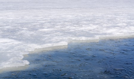 Edge between snow and frozen water are on winter lakeの写真素材
