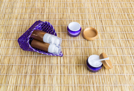 Open jar with cream for face or body, empty container and airless dispensers for cosmetic are on matの写真素材