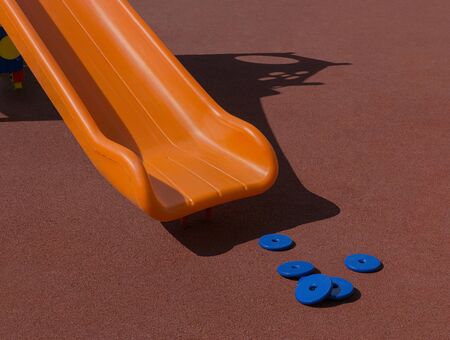 Plastic chute of slide is on playground with coating crumb rubber. Sunny day. Copy space