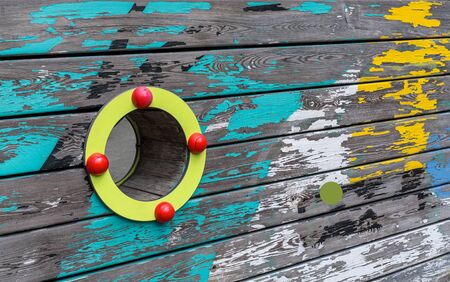 Porthole is on old worn plank wall with patches of yellow, blue and white paint. Wood texture, backgroundの写真素材