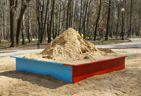 Heap of sand in wooden sandbox is on the playground in park. Spring sunny dayの写真素材