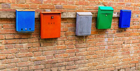 Metal mailboxes of different colors hangs on old brick wall. Copy spaceの写真素材