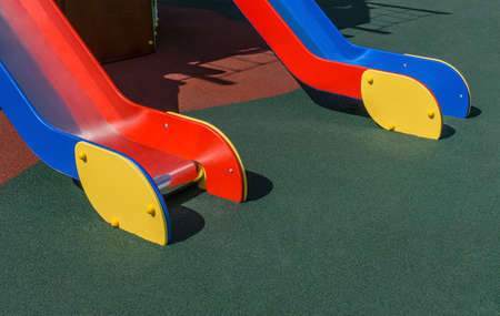Two wooden chutes of slides are on playground with coating crumb rubber. Sunny day. Copy space