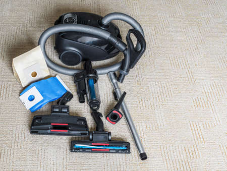 Vacuum cleaner with flexible hose and various attachments lie on carpet. Top view. Copy spaceの写真素材