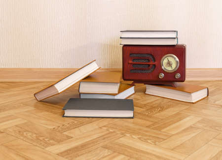 Wooden retro radio receiver and pile of books are on floor near wall. Copy space. Small depth of fieldの写真素材