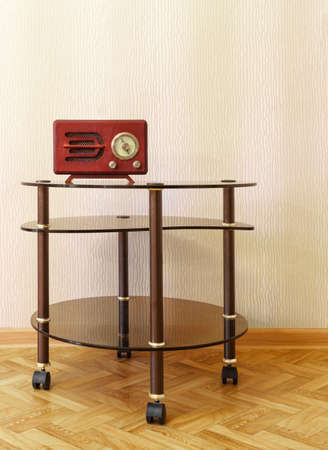 Wooden retro radio receiver is on glass coffee table near wall. Copy spaceの写真素材