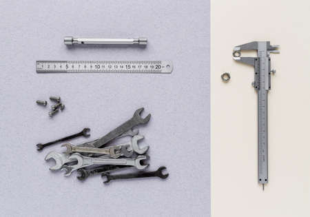Caliper, ruler, spanners and screws are on paper background. View from above
