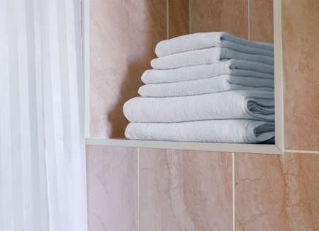 Stack of white terry towels are in alcove of wall. Fragment of bathroom interiorの写真素材