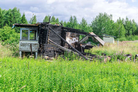 Remains of wooden country house after conflagration in abandoned suburban plotの写真素材