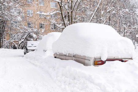 Cars completely covered with snow after heavy snowfall are in courtyard of residential building....