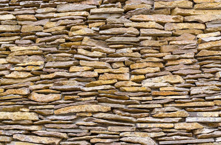 Fragment of wall made of flat stones held together with cement mortar. natural texture backgroundの写真素材