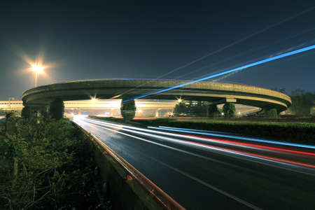 Large urban ring highway viaduct long exposure photo light trails night sceneの写真素材