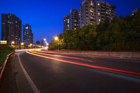 The urban background of modern office buildings car night light trails in Shanghaiの写真素材