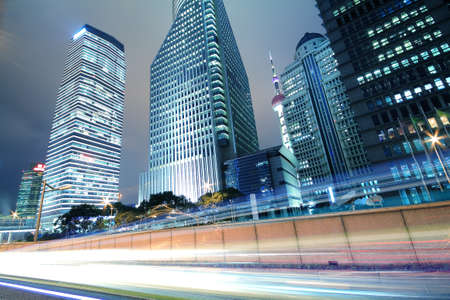 The urban background of modern office buildings car night light trails in Shanghaiの写真素材