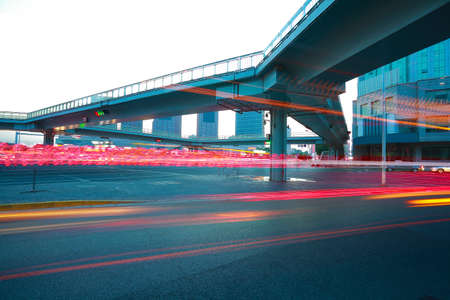 Intersection of urban footbridge and highway auto with light trails of night sceneの写真素材