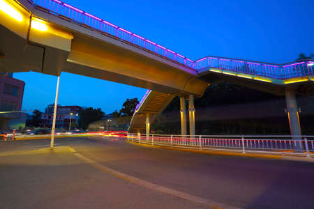 Intersection of urban footbridge and highway auto with light trails of night sceneの写真素材